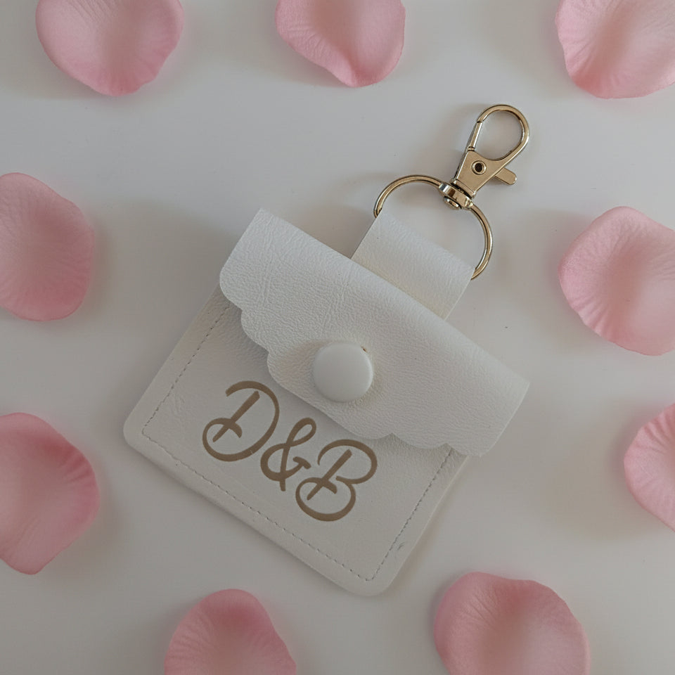 White dog wedding ring pouch with gold clasp and initials on a light background