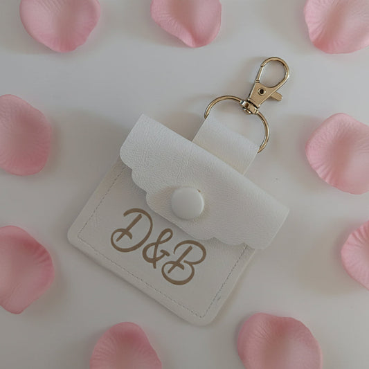 White dog wedding ring pouch with gold clasp and initials on a light background
